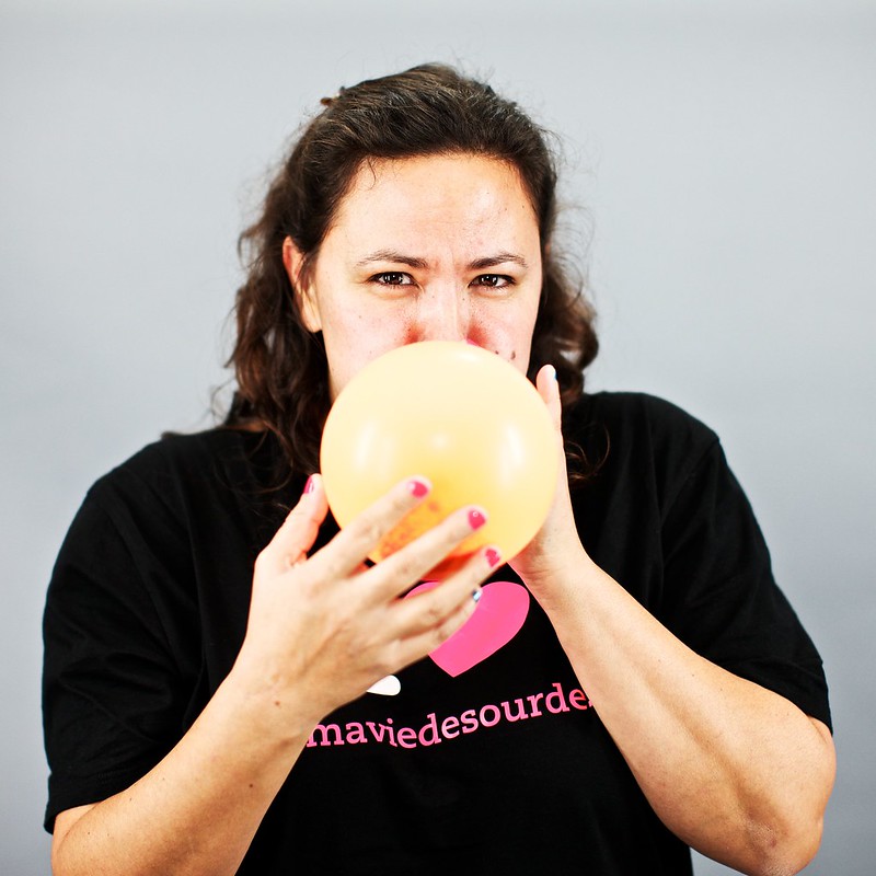 Sophie en train de souffler dans un ballon, le regard fixe sur l'objectif